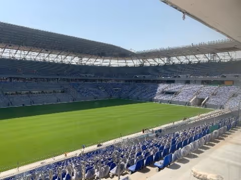 Ras Abu Aboud Stadium seen from the stadium seating section on a bright, sunny day.