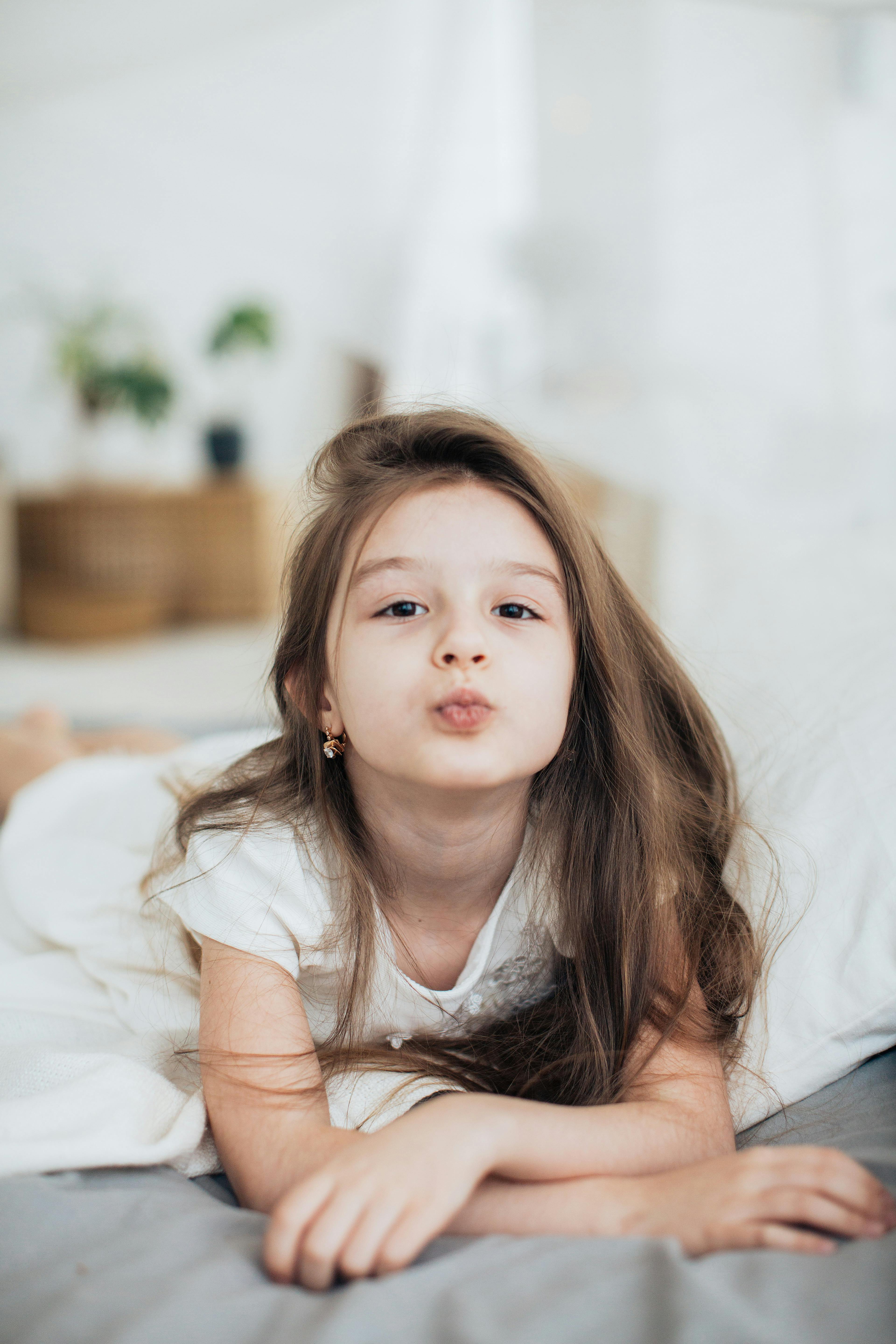 A little girl blows a kiss to the camera ; White background