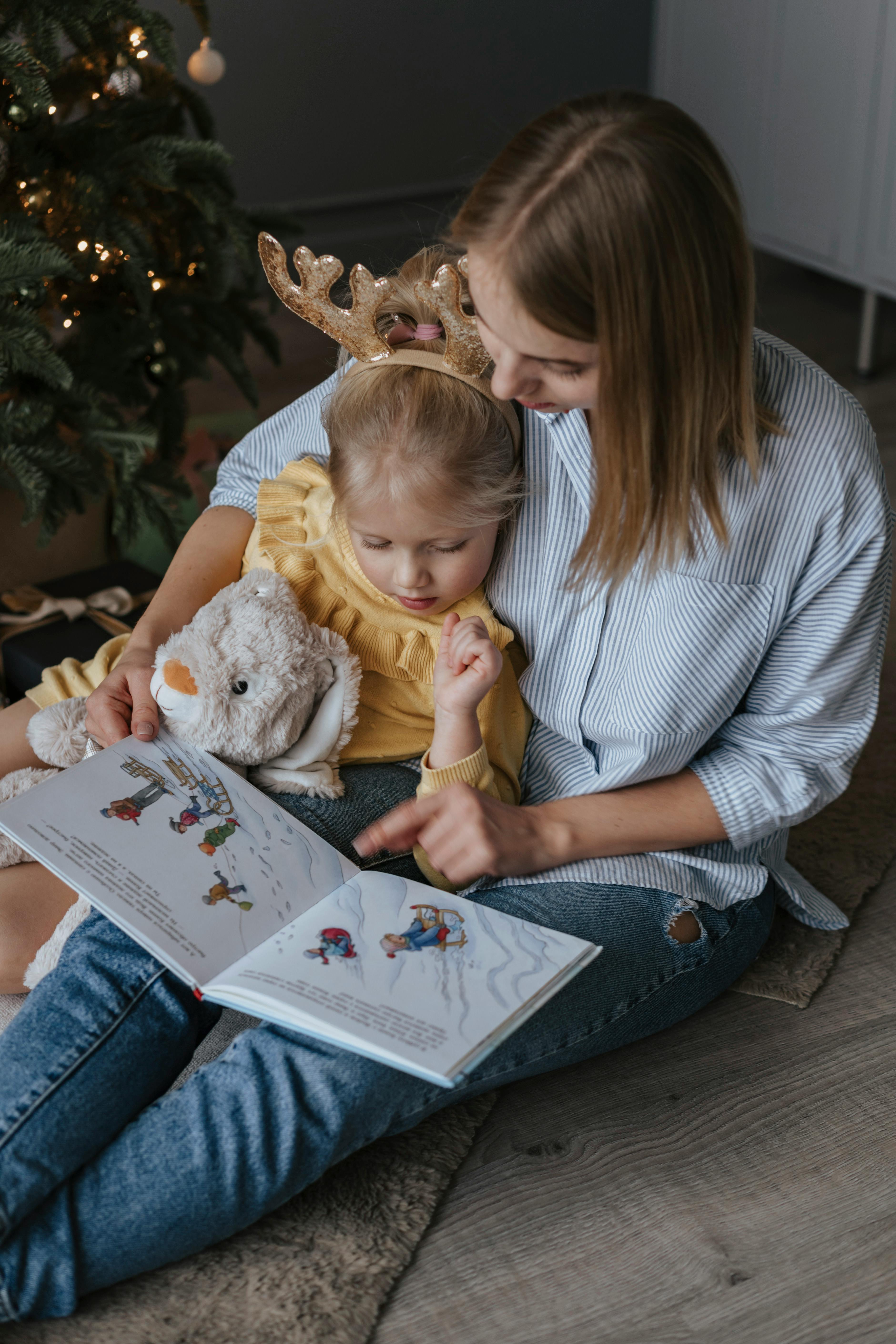 A woman reads a story to a blonde little girl on her lap.