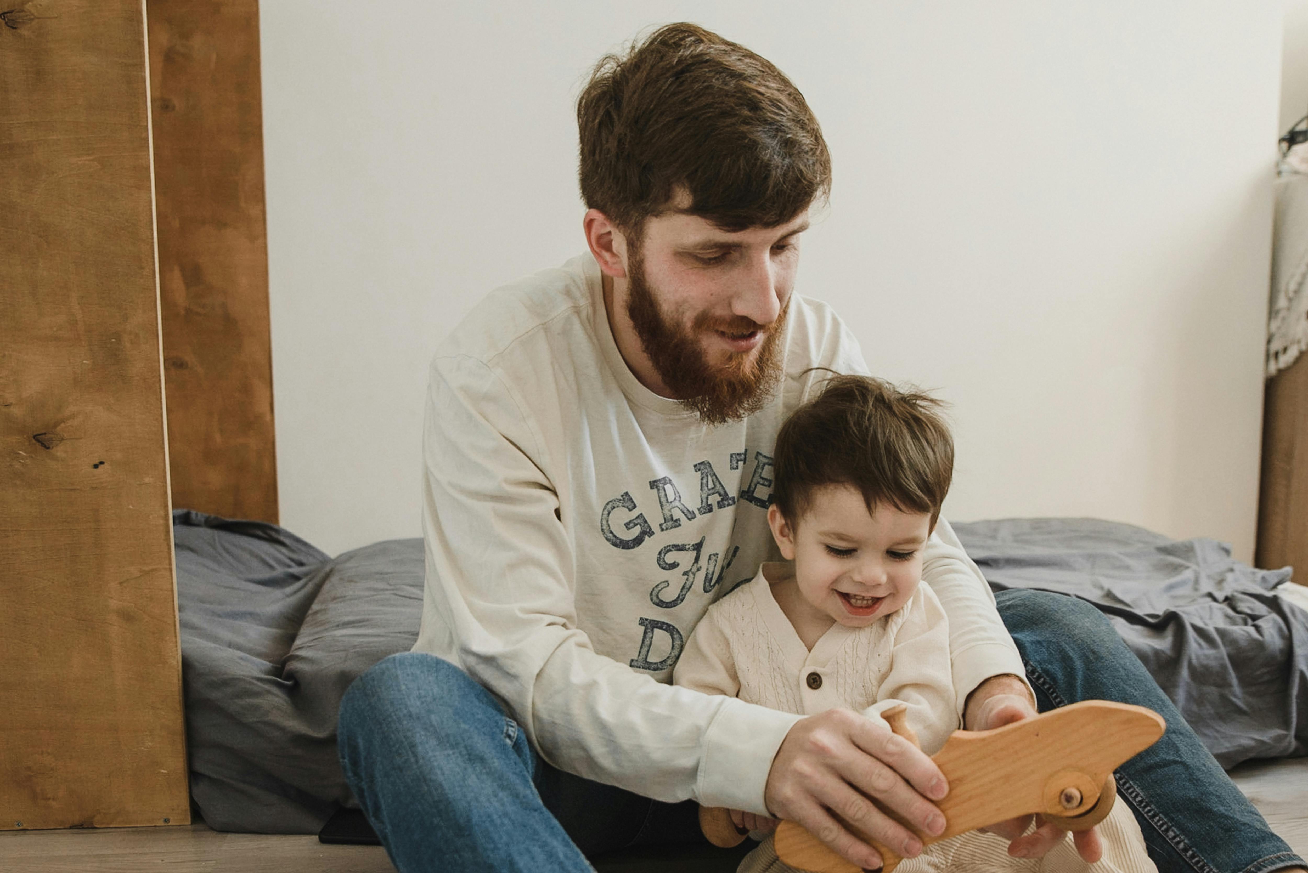 A man plays with a wooden toy with a child