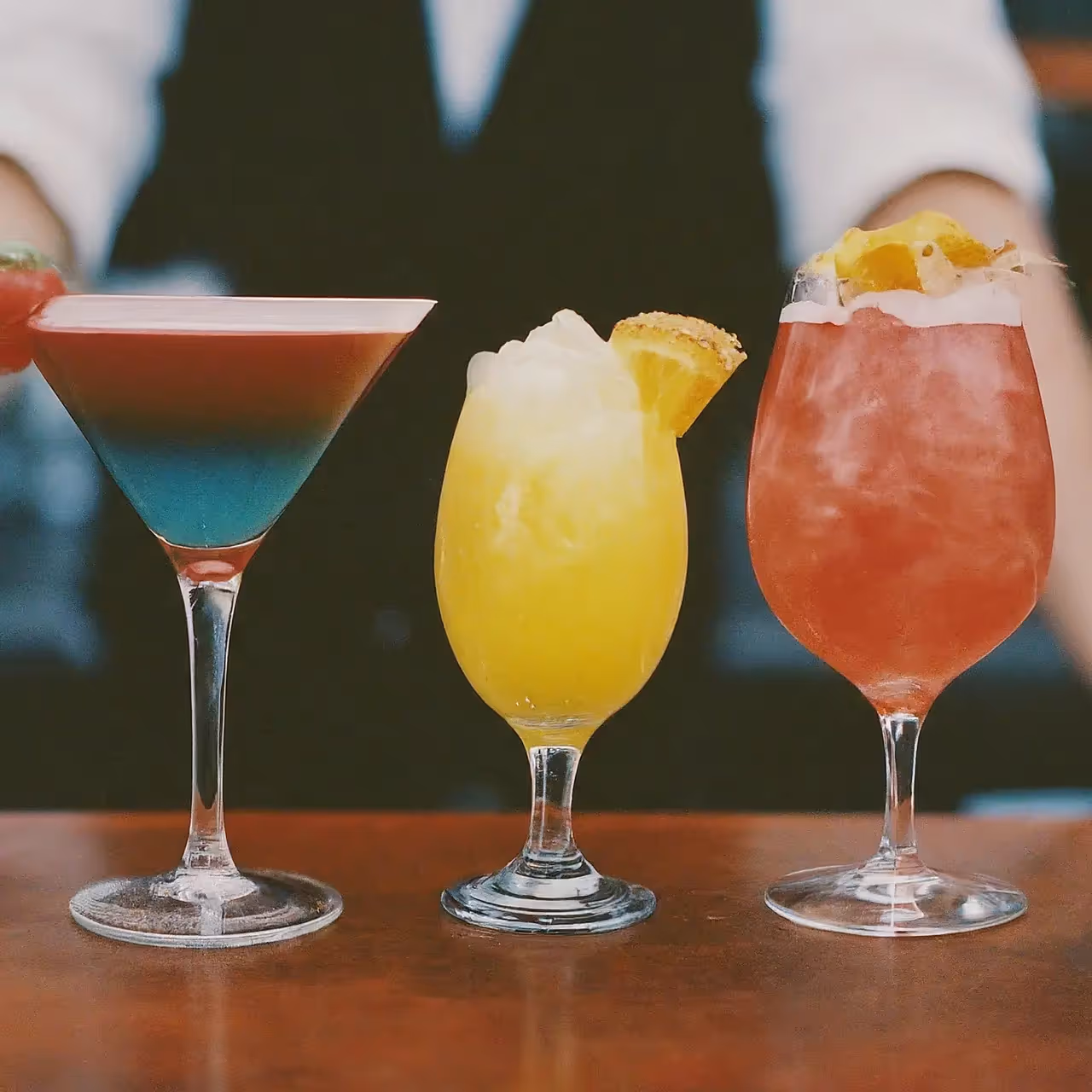 Various colorful cocktails lined up on a bar counter. 35mm stock photo
