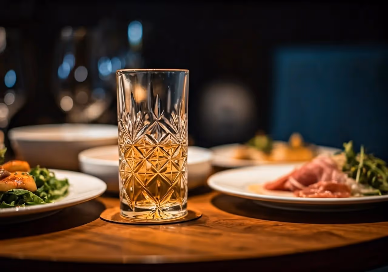 A crystal glass of tequila with gourmet food on a table. 35mm stock photo