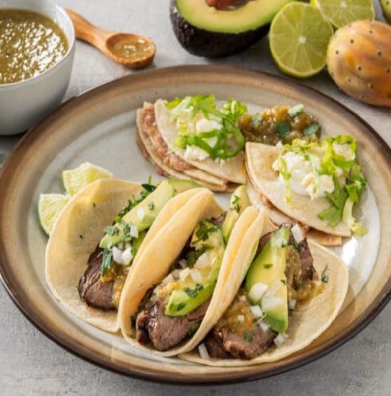 A plate of food with meat and avocado on top.
