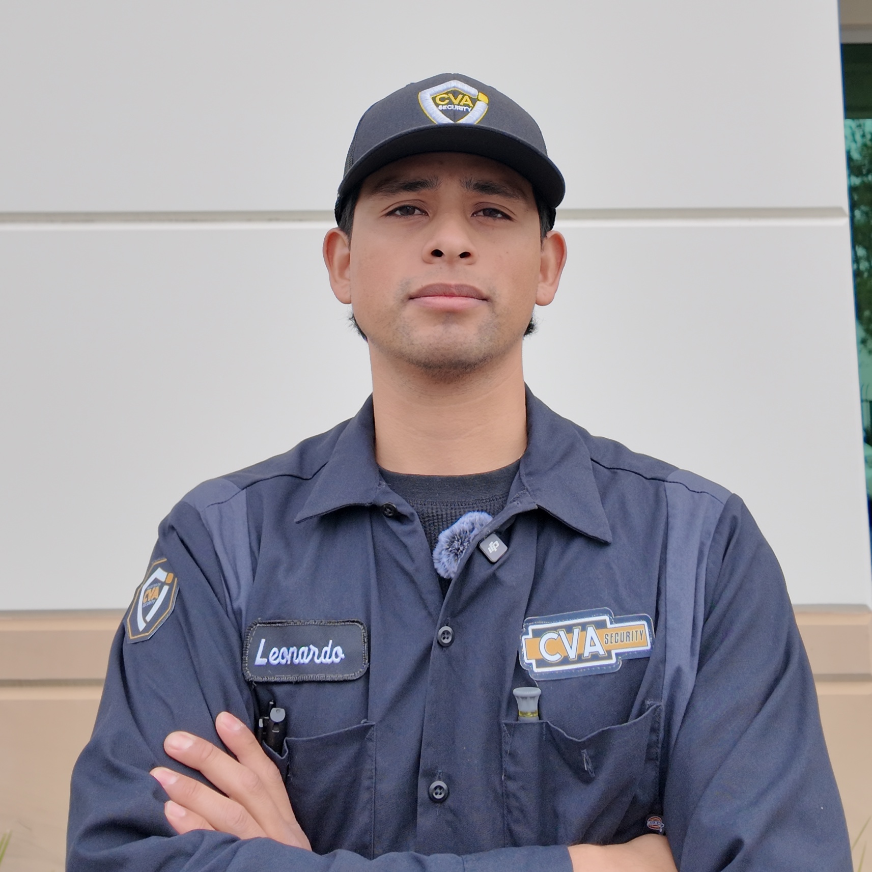 Portrait of a security guard named Leonardo with arms crossed, wearing a navy CVA Security uniform and cap.