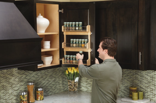 Man opening a dark wood kitchen wall cabinet with a door-mounted spice rack in an Edmonton kitchen