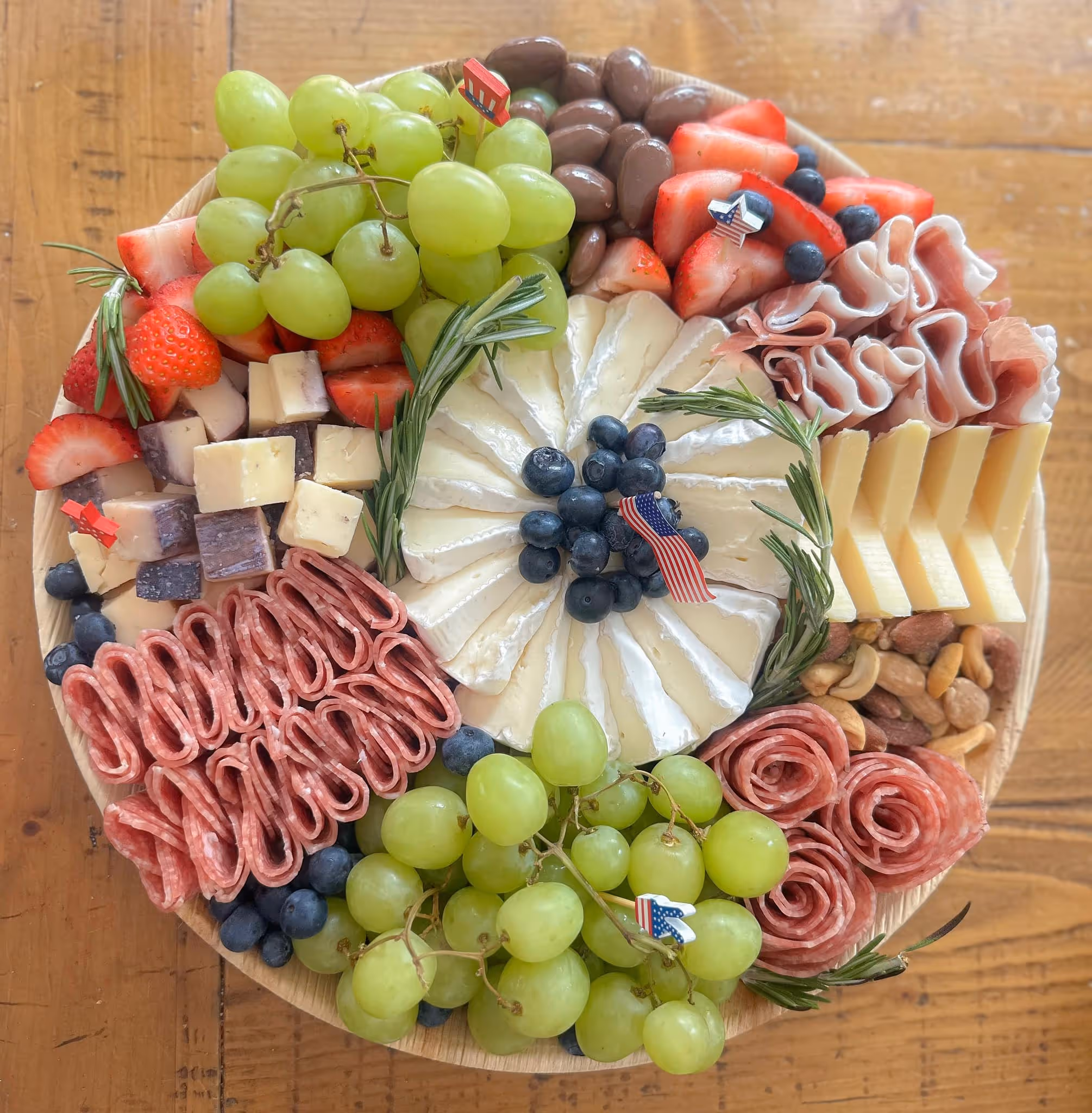 charcuterie board with cheese, ham, fruits, salami, olives, jam, chocolate, and nuts