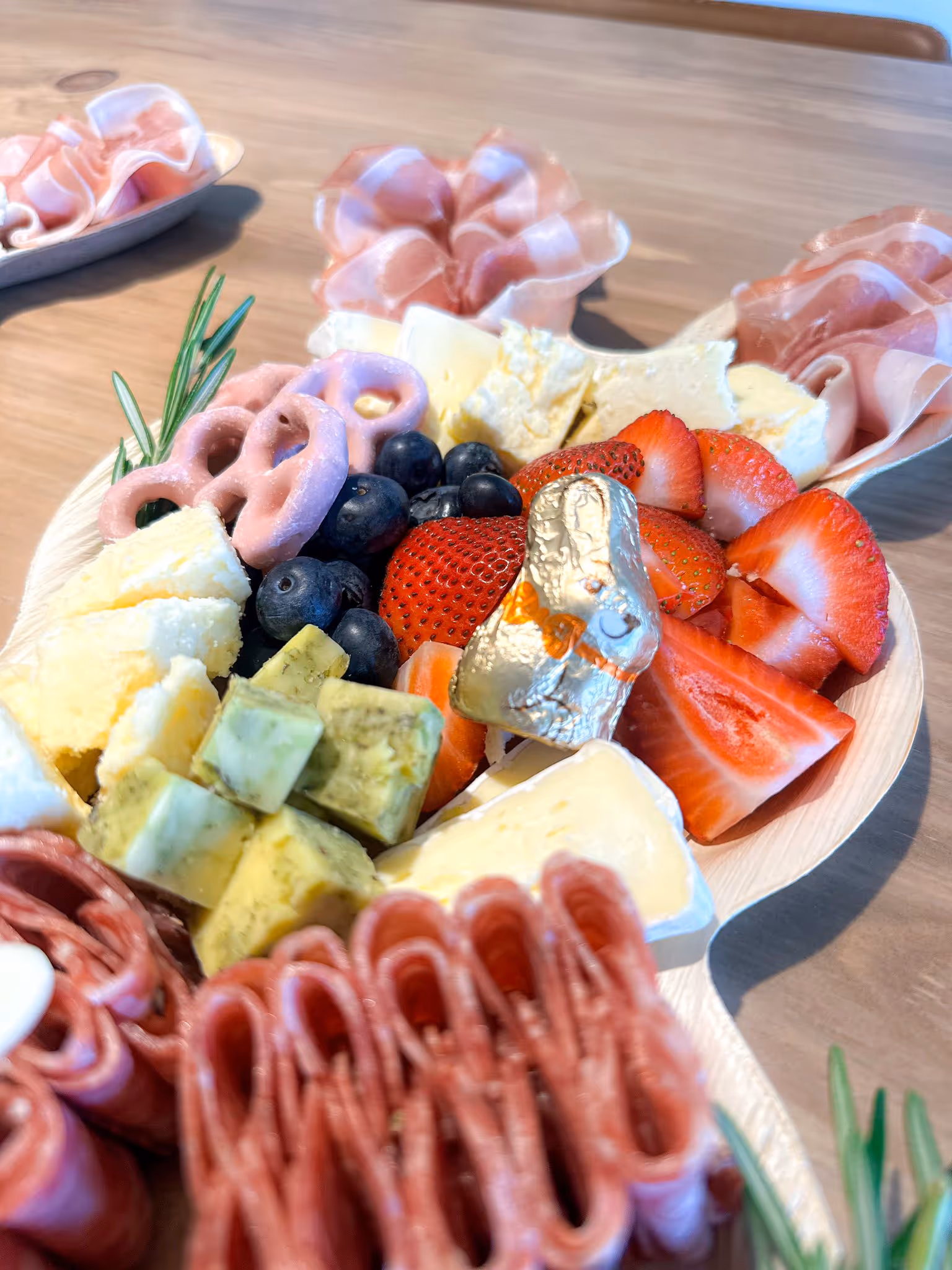 charcuterie board with cheese, ham, fruits, salami, olives, jam, chocolate pretzel