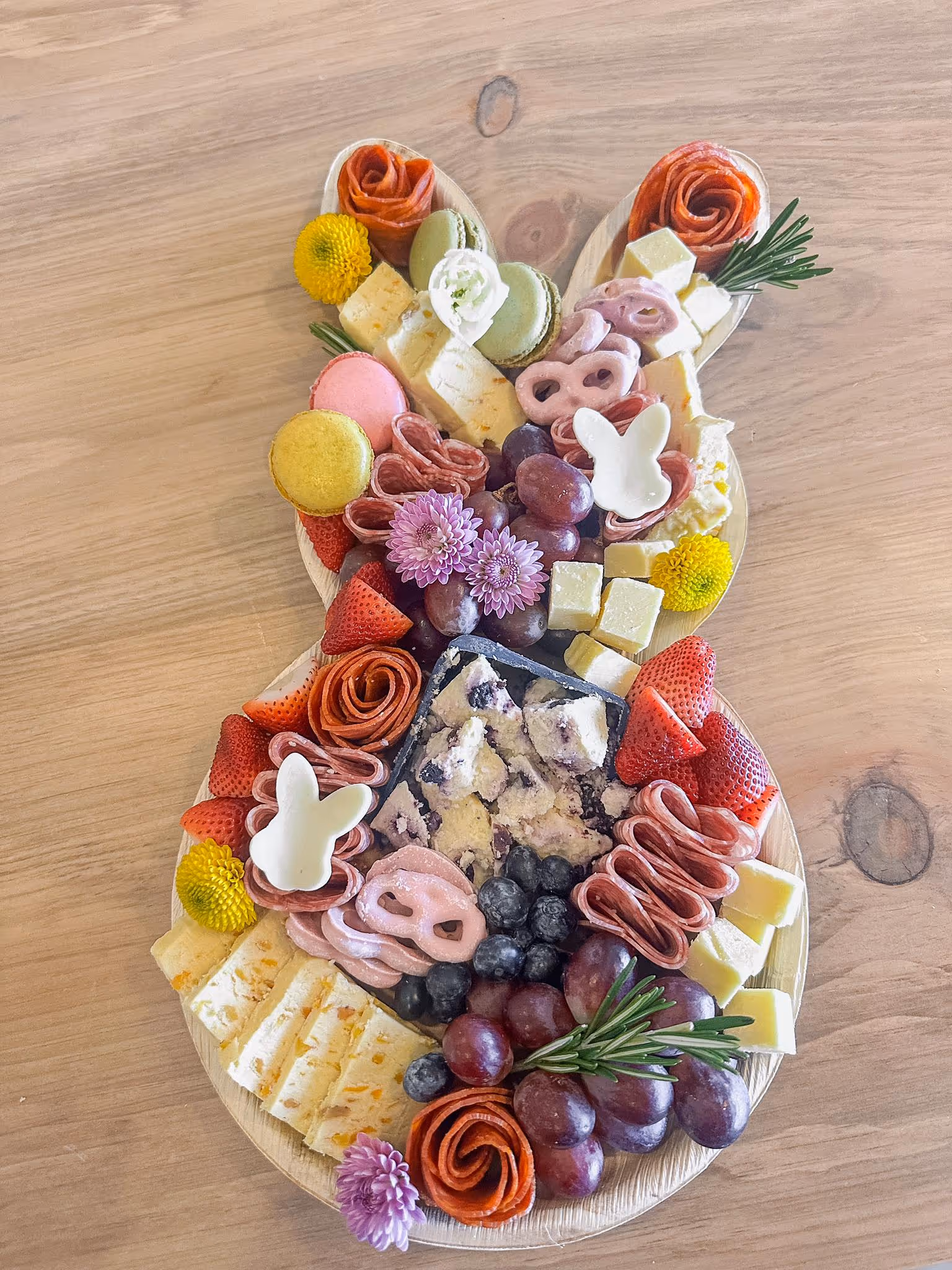 charcuterie board on a bunny with cheese, ham, fruits, salami, olives, jam, chocolate, and nuts