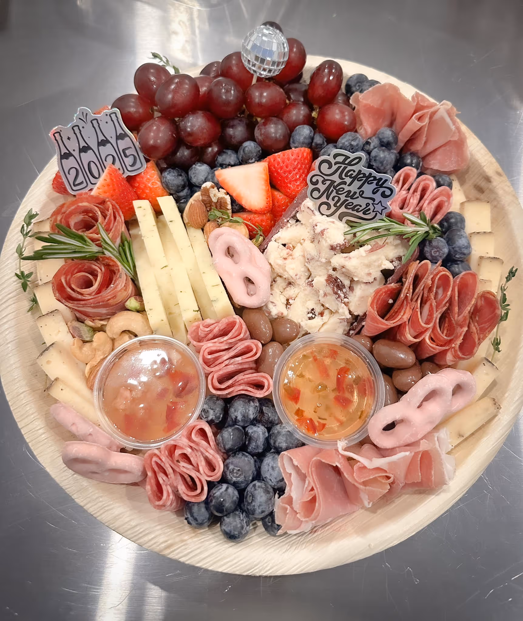 New Years charcuterie board with cheese, ham, fruits, salami, olives, jam, chocolate, and nuts