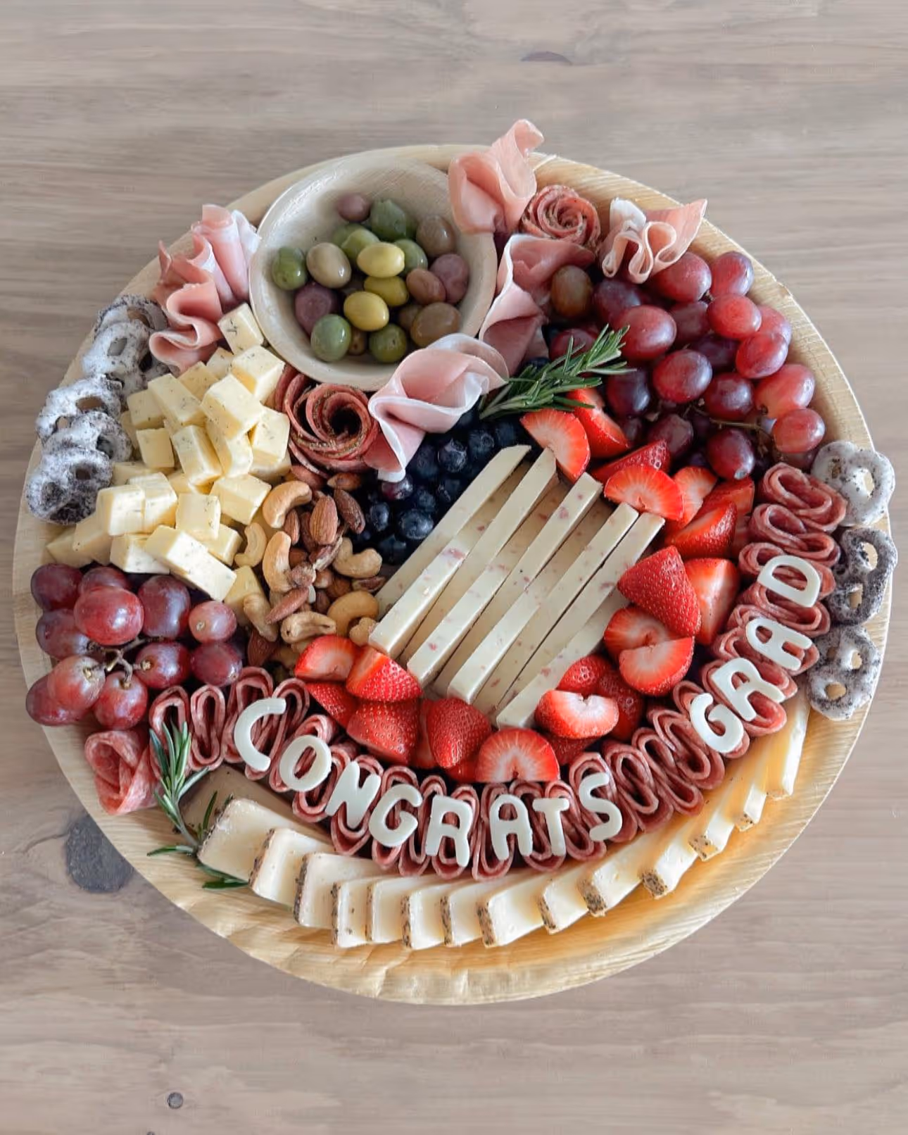 charcuterie board for graduation with cheese, ham, fruits, salami, olives, jam, chocolate, and nuts