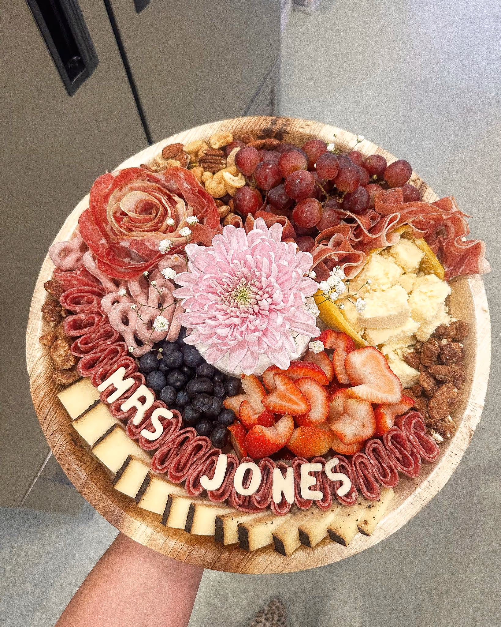 charcuterie board with cheese, ham, fruits, salami, olives, jam, chocolate, and nuts