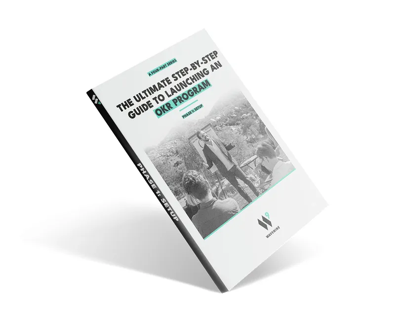 An angled view of the cover for the Wavenine ebook guide on launching an OKR program. The title reads, "The Ultimate Step-by-Step Guide to Launching an OKR Program - Phase 1: Setup."