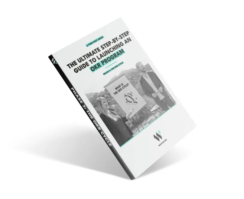 An angled view of the Wavenine ebook cover for "Phase 3: The OKR Cycle," which is part of a four-part series on launching a successful OKR program. The cover image shows two coaches discussing the OKR cycle.