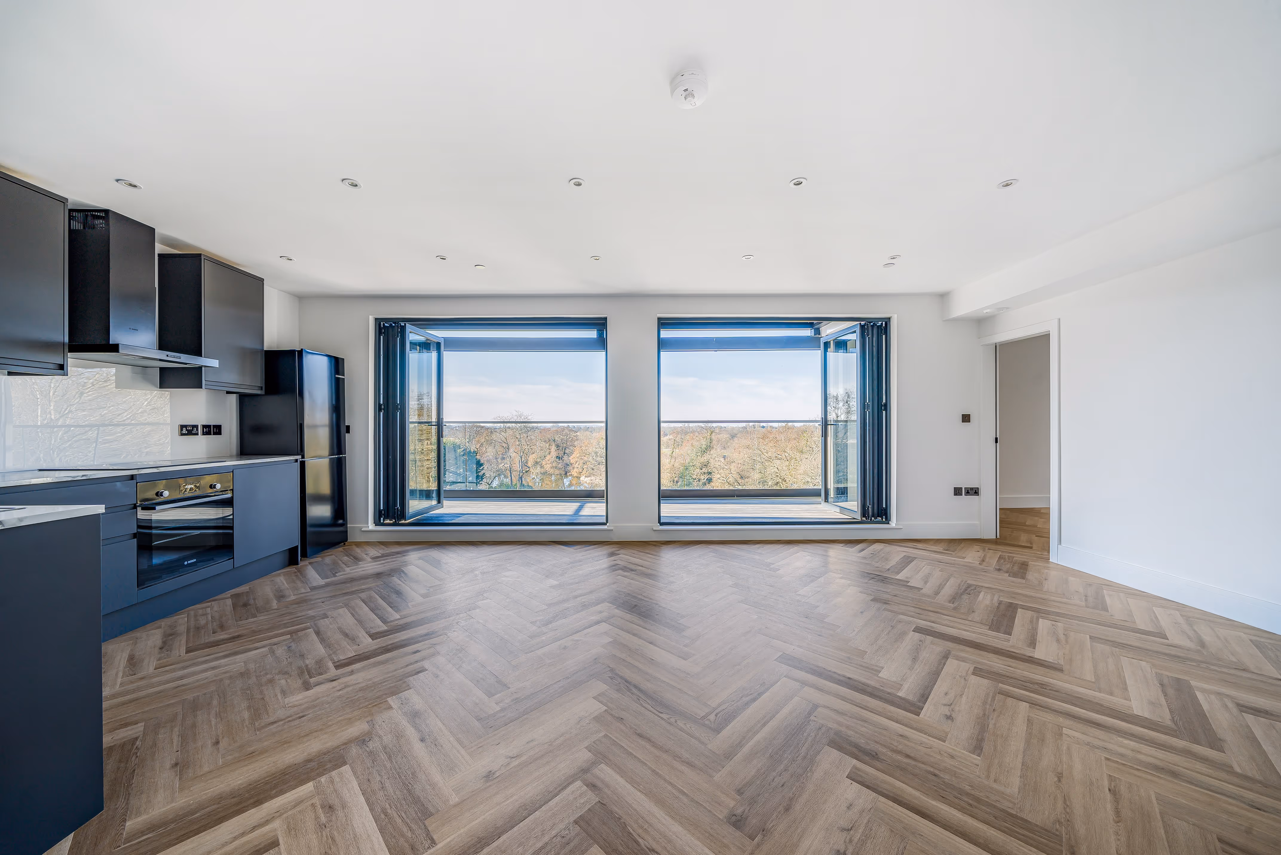 Living/kitchen open plan area with open bifold doors showing the horizon outside.