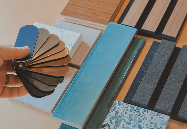 A set of textures and colour palettes spread across a table. A hand holds a colour palette book spread out