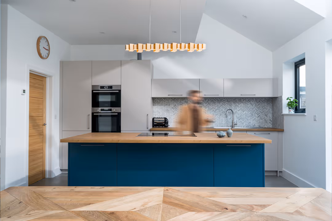 An interior shot of a modern kitchen with a blurred image of a man cooking. This was an interior project in Chartfield