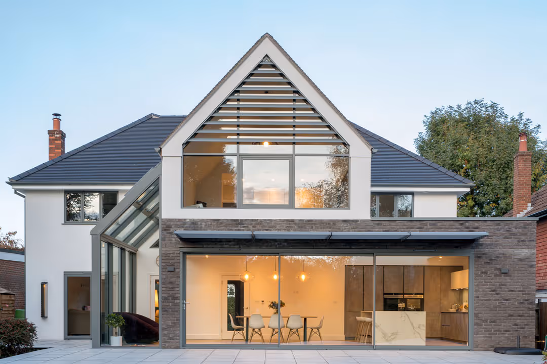 An exterior shot of a house at dusk. The kitchen can be seen through the large windows. This was an architectural project in Carlton