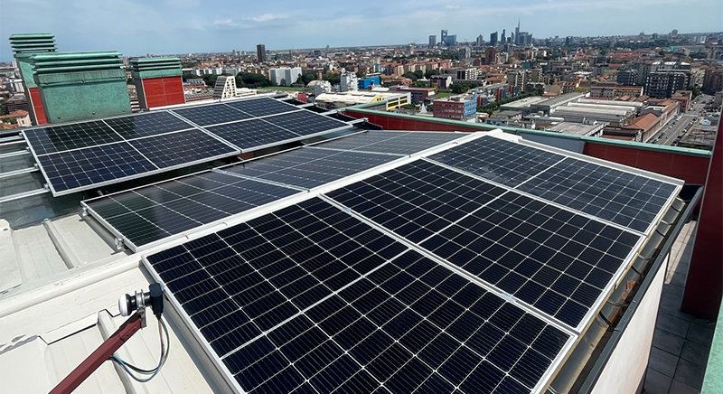 Solar panels installed on a rooftop overlooking a cityscape with clear skies.