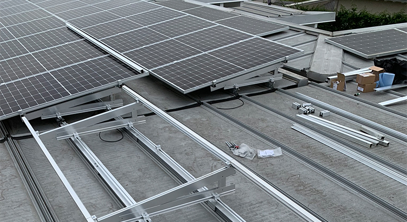 Partially installed solar panels on a rooftop with metal frames and installation tools visible.