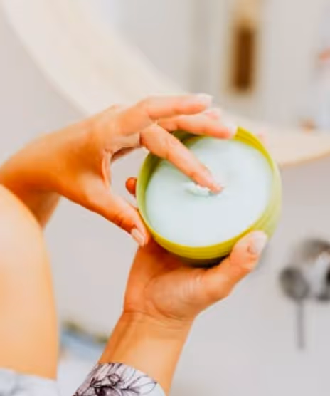 woman's hands picking up some product out of a pot of body balm