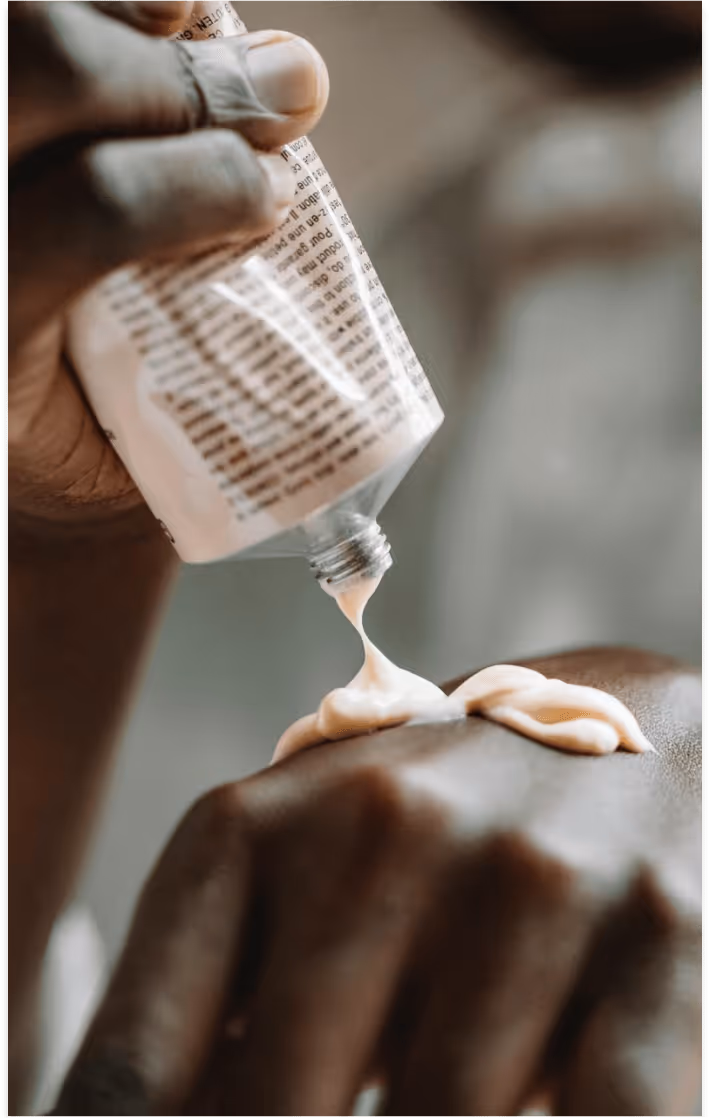 closeup of dark skinned person's hands putting on a hand cream
