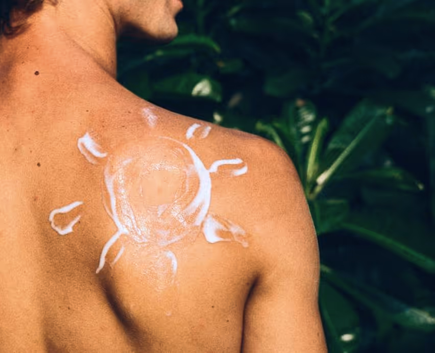 man with sunscreen on back in shape of a sun