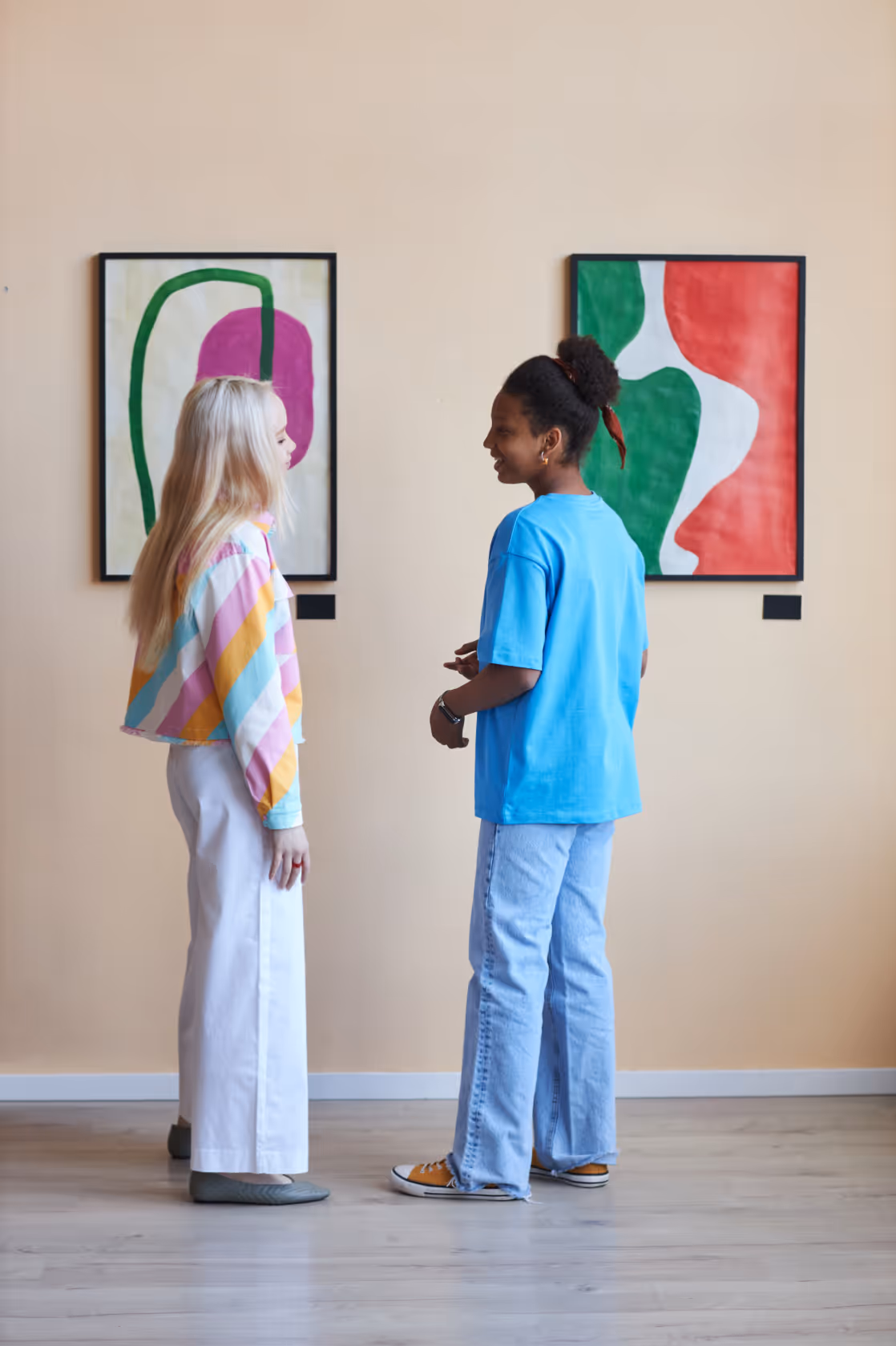 Two young people talking while viewing modern artwork in a gallery, representing the local cultural attractions near Jefferson Arms in St. Louis, MO.