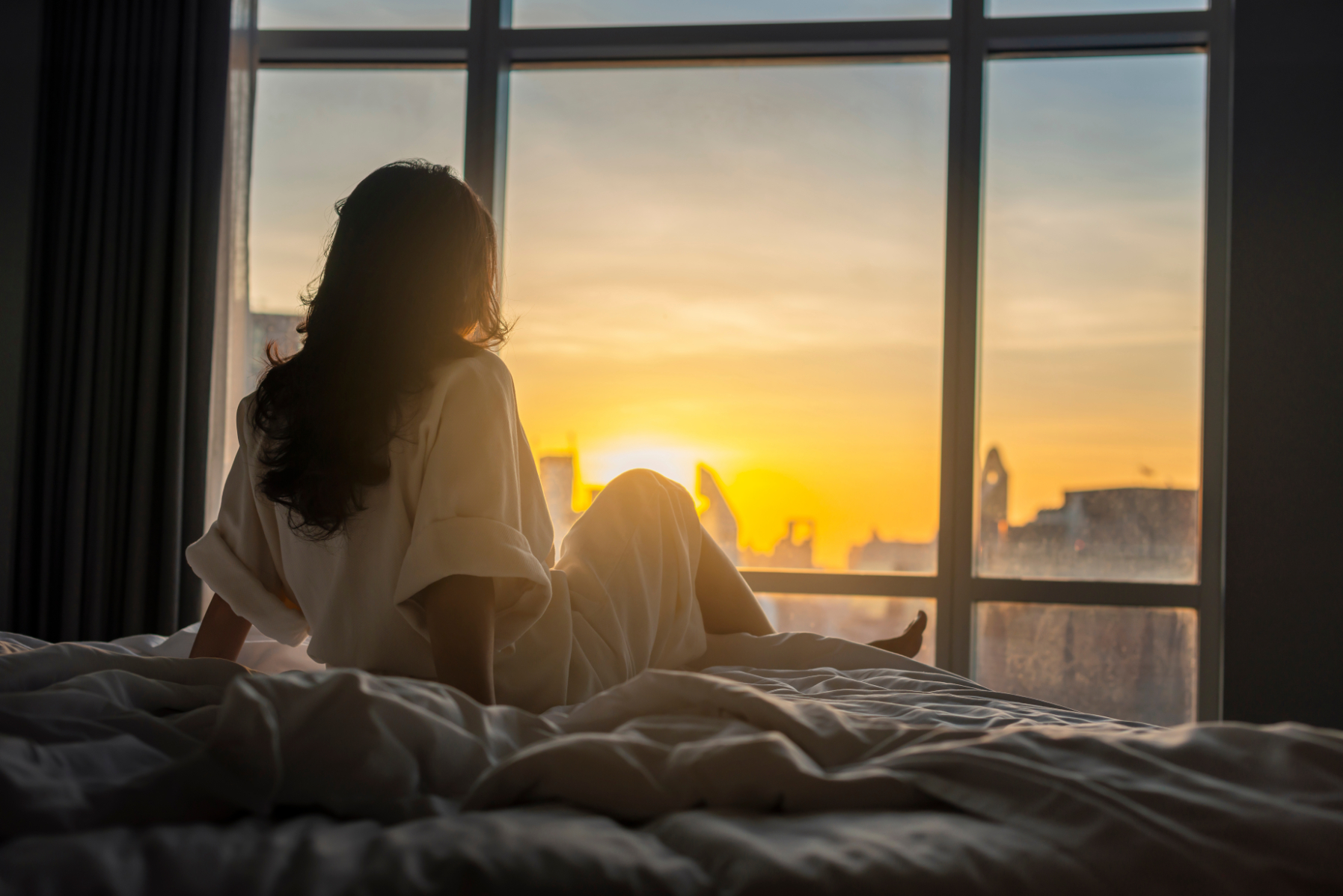 woman on bed looking out window stock image