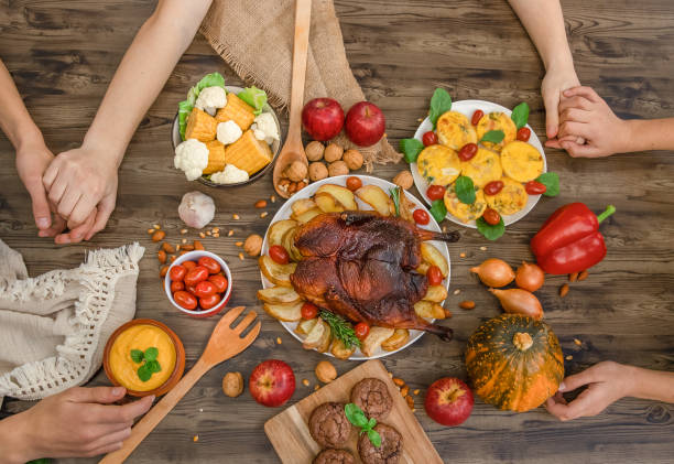 people holding hands, thanksgiving dinner served on wooden background, cooked turkey or chicken with vegetables, November celebration, concept of thanks-fullness and togetherness people holding hands, thanksgiving dinner served on wooden background, cooked turkey or chicken with vegetables, November celebration, concept of thanks-fullness and togetherness. Festive table close-up showing various Thanksgiving stock pictures, royalty-free photos & images