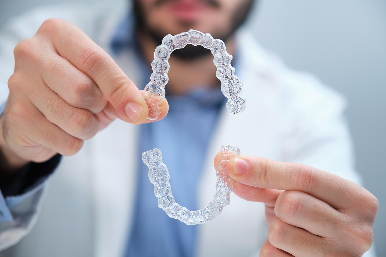 Close-up of clear Invisalign aligners held by a dental professional.