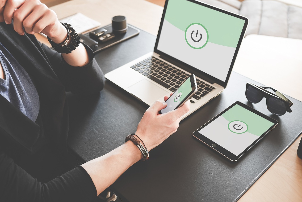 Photo of a woman at her desk. Laptop on the desk. Tablet on the desk. Phone on the desk. Remote working. Work from home