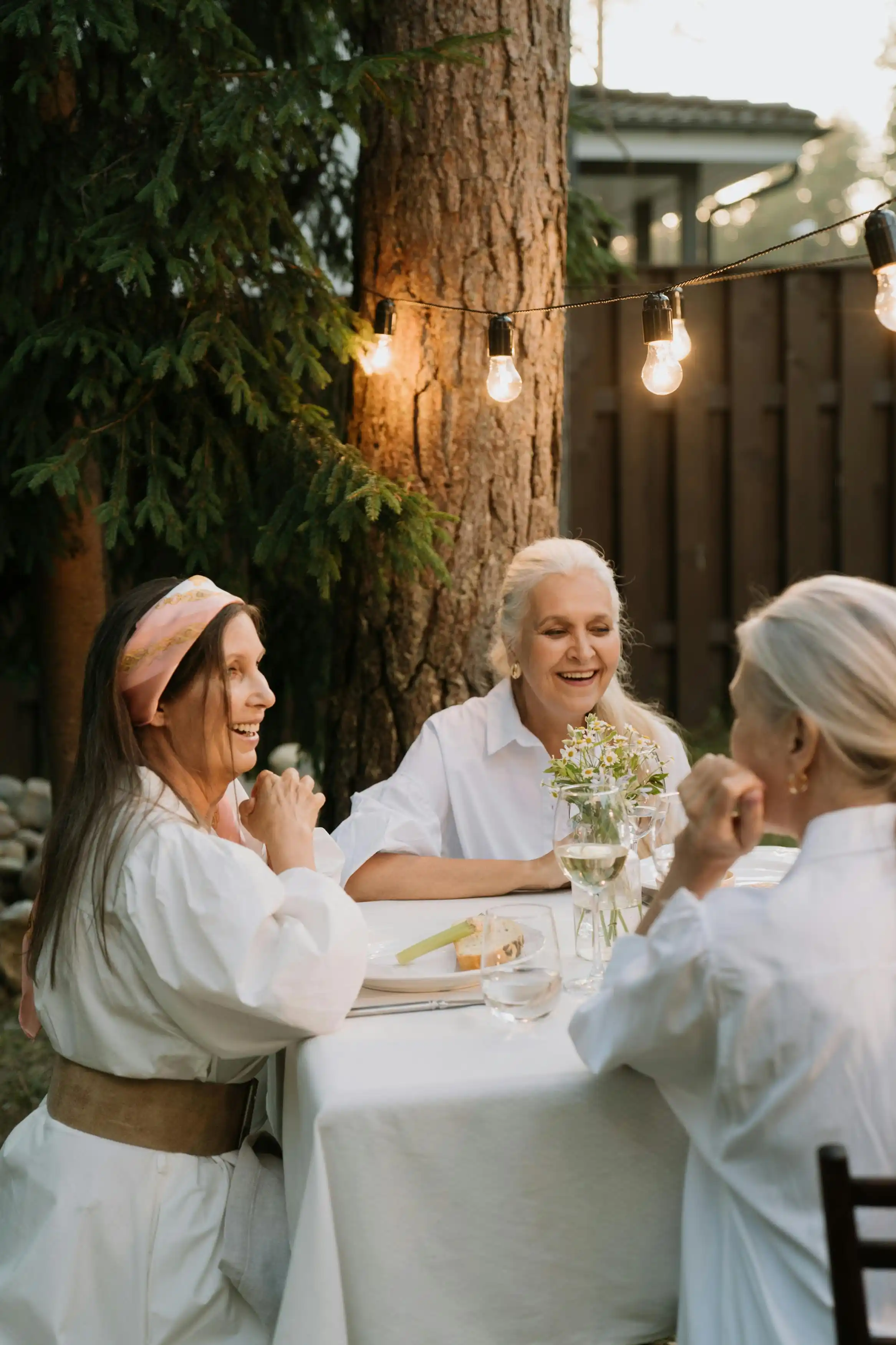Women gathered around a backyard table, laughing together.