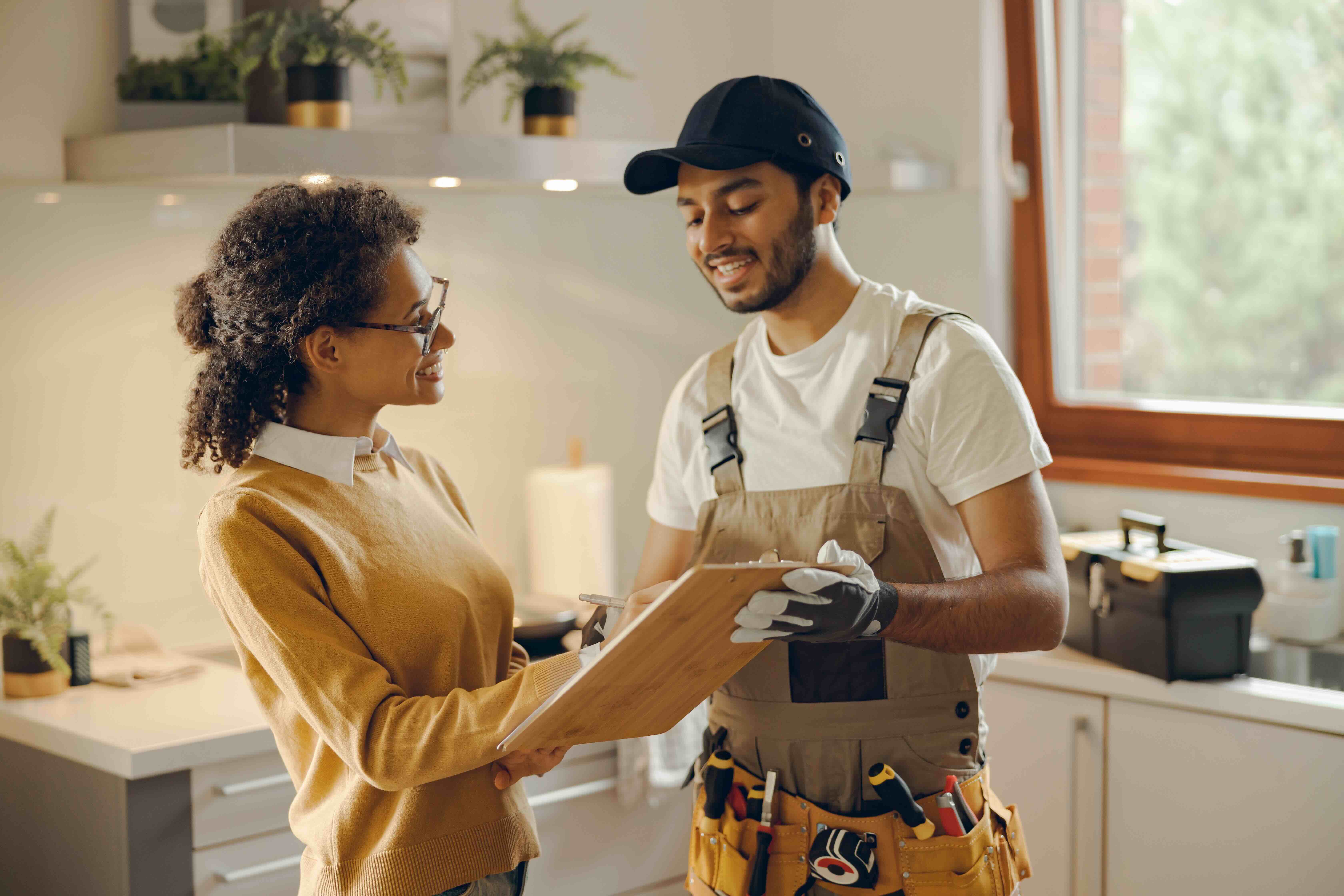 A woman is having a productive conversation with her maintenance professional and they are both smiling.