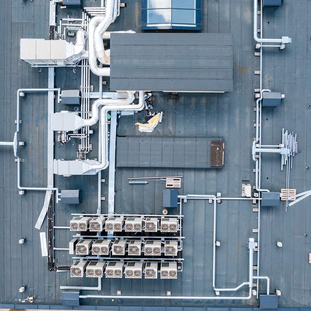 Aerial view of commercial rooftop HVAC system with ductwork, ventilation units, and air conditioning condensers