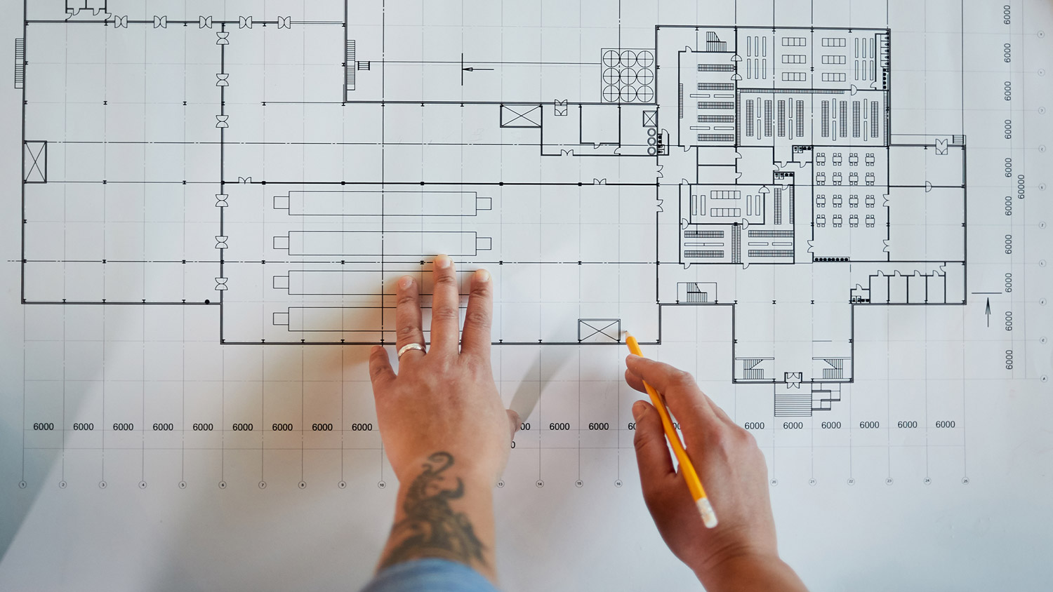 Reviewing detailed building floor plan with pencil