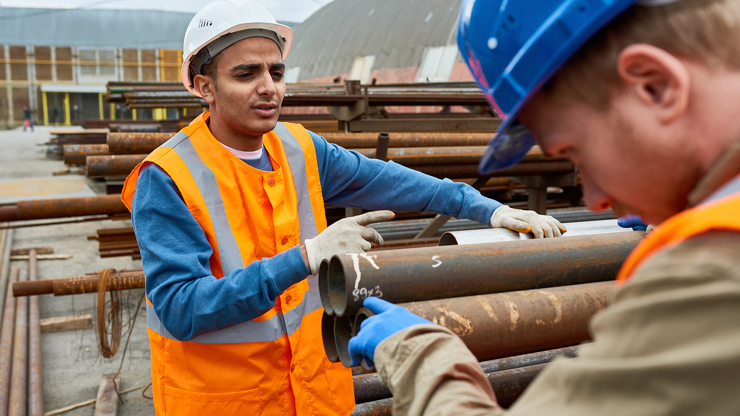 Workers inspecting steel pipes at a job site