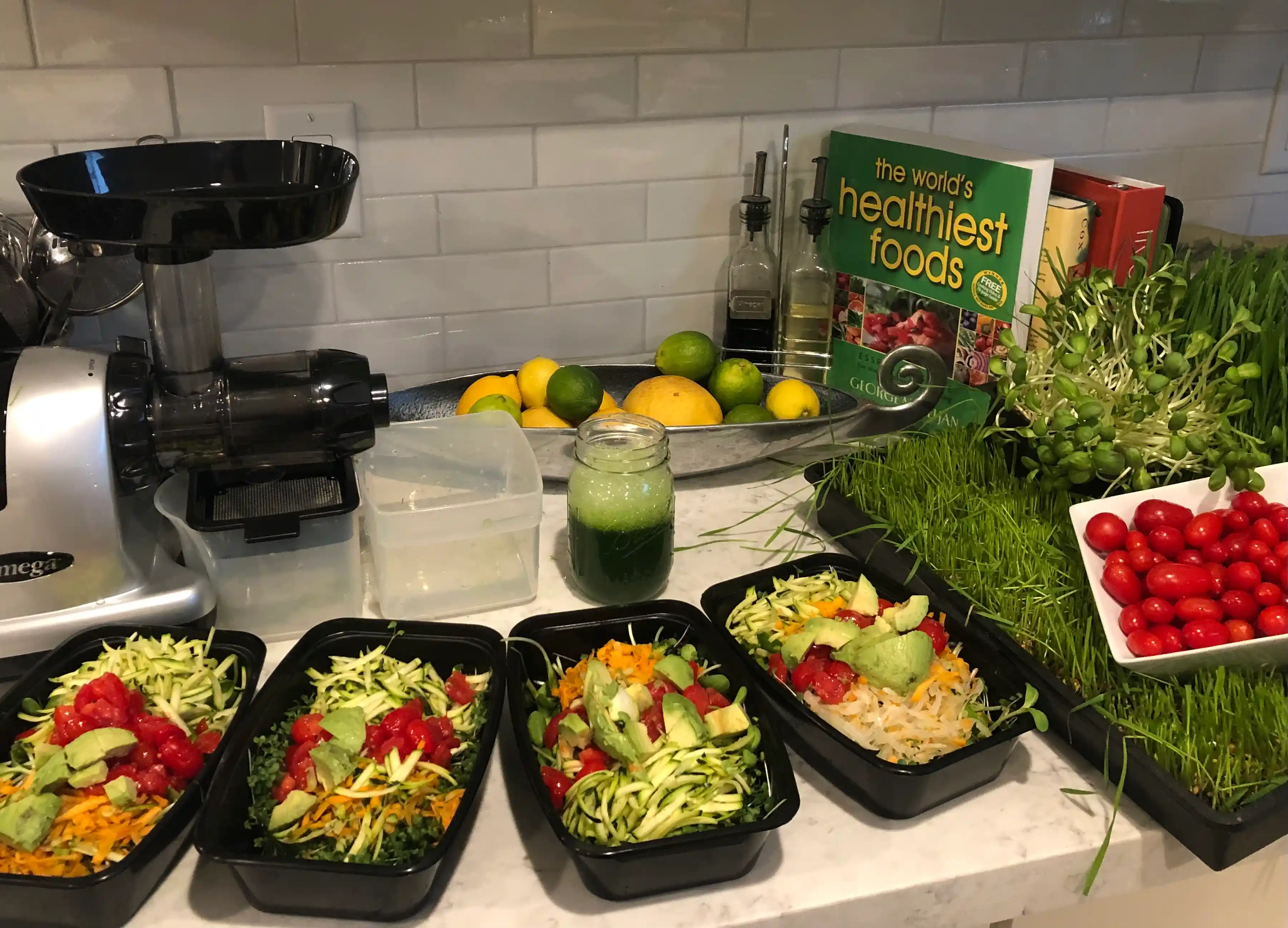 Kitchen counter with a juicer, fresh fruits, sprouts, and meal prep containers filled with shredded vegetables, avocado, and tomatoes, highlighting holistic health, women’s empowerment, and mindful living in midlife.