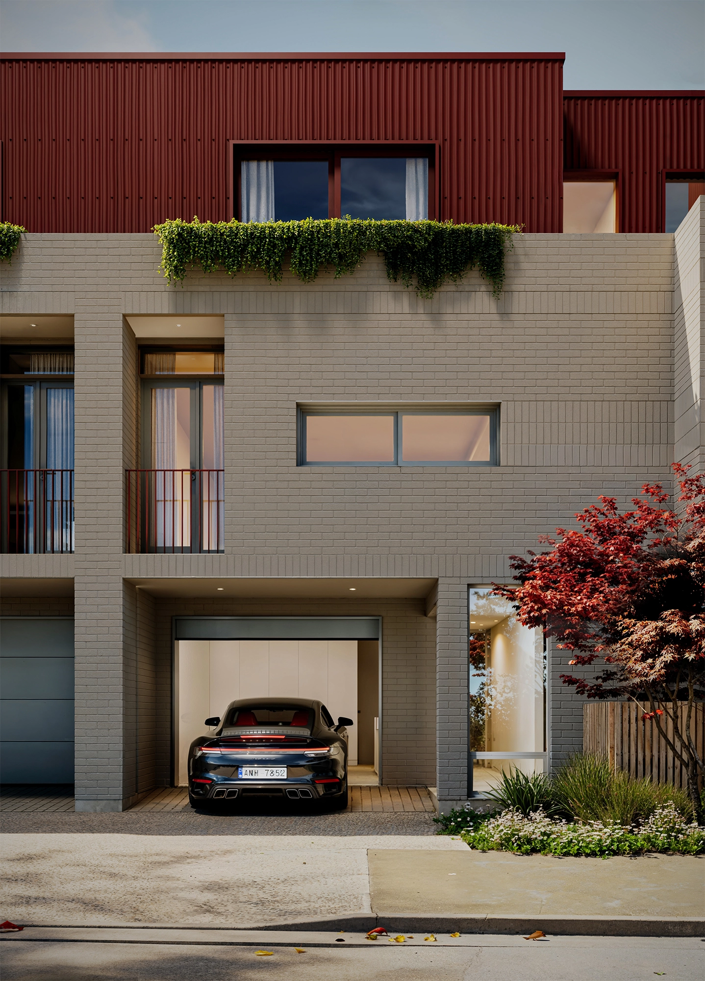 Modern townhouse with beige brick facade, a black car in an open garage, and a red tree on the right side.