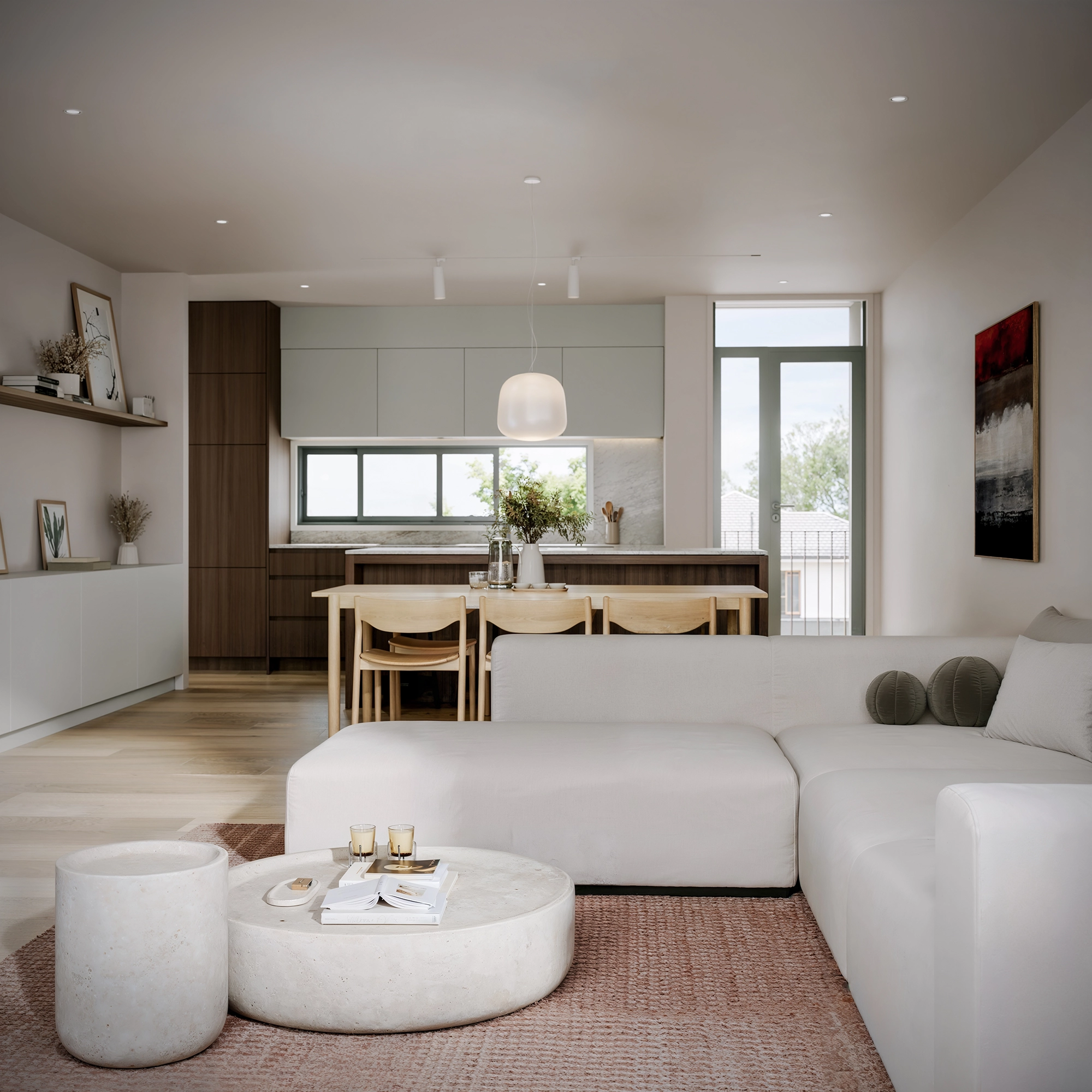 Modern living room with white sectional sofa, round stone coffee tables, dining area, and kitchen in background.
