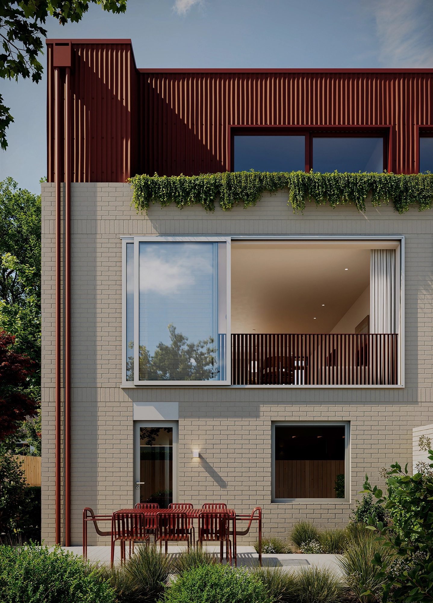 Modern two-story home exterior with beige brick, red metal upper facade, balcony, and outdoor dining area.