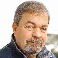 Middle-aged man with short gray hair and a gray beard wearing a dark jacket.