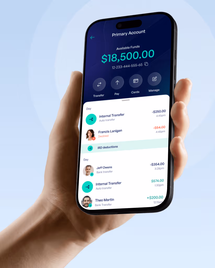 Hand holding smartphone displaying a banking app showing a primary account with $18,500 available, recent transactions including internal transfers and payments.