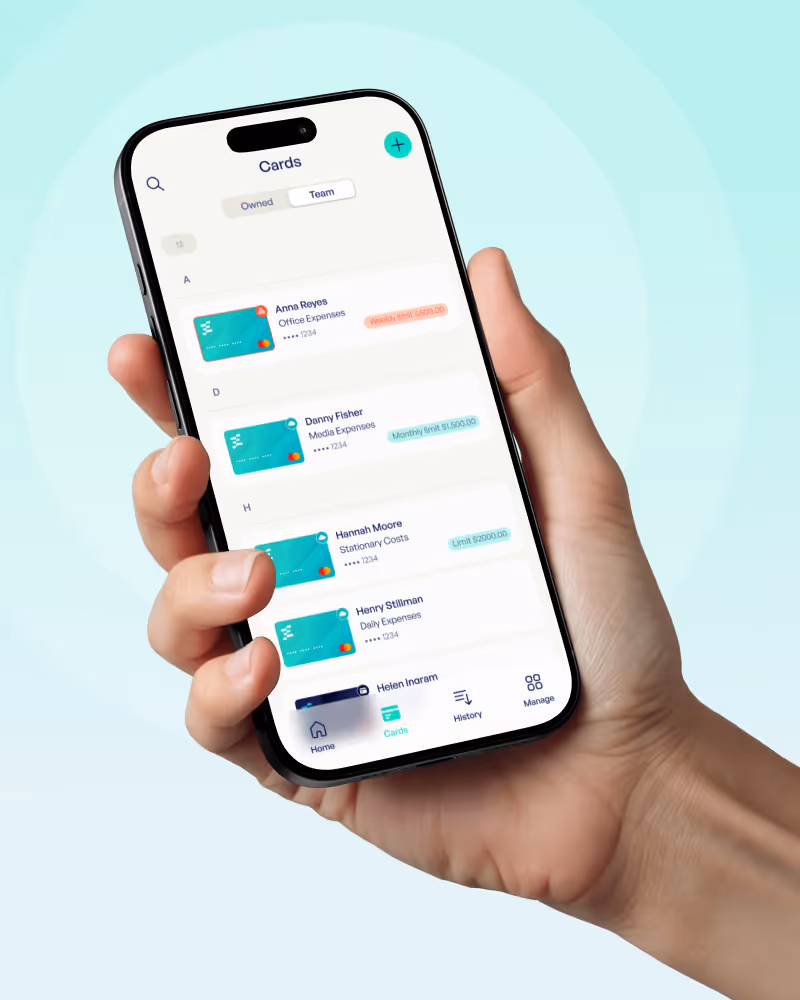 Hand holding a smartphone displaying a finance app screen with team cards for Anna Reyes, Danny Fisher, Hannah Moore, and Henry Stillman, including expense categories and spending limits.