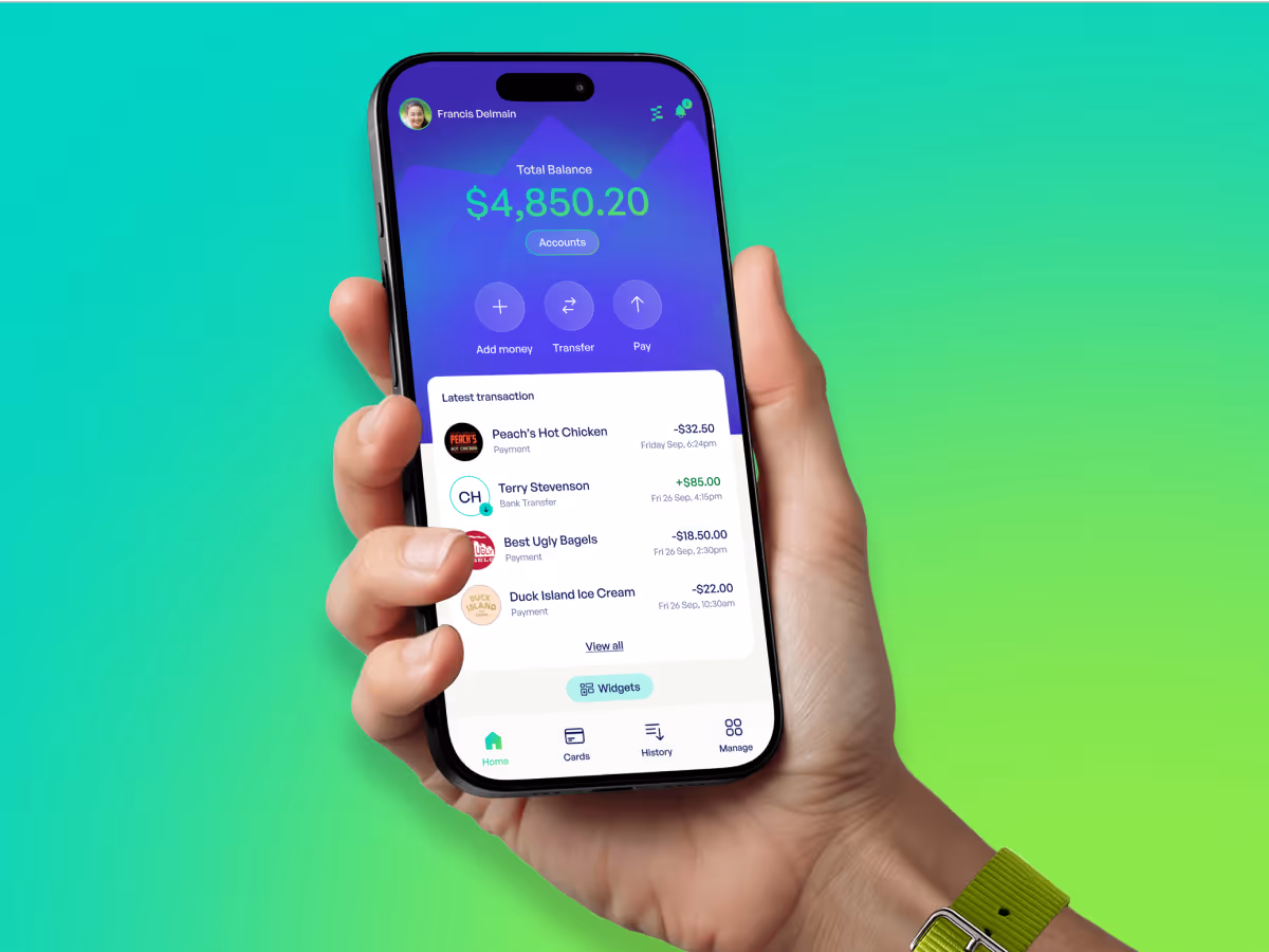 Hand holding smartphone showing a financial app with a total balance of $4,850.20 and recent transactions from Peach’s Hot Chicken, Terry Stevenson, Best Ugly Bagels, and Duck Island Ice Cream.