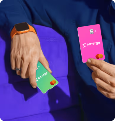 Person holding two Mastercard credit cards, one pink and one green, both branded with 'emerge'.