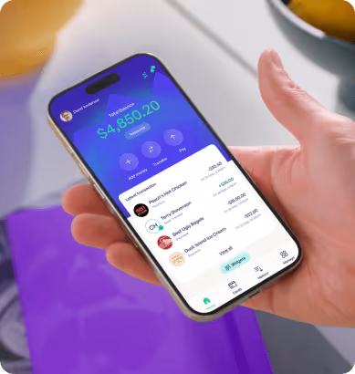 Hand holding smartphone displaying a banking app with a total balance of $4,850.20 and recent transactions.