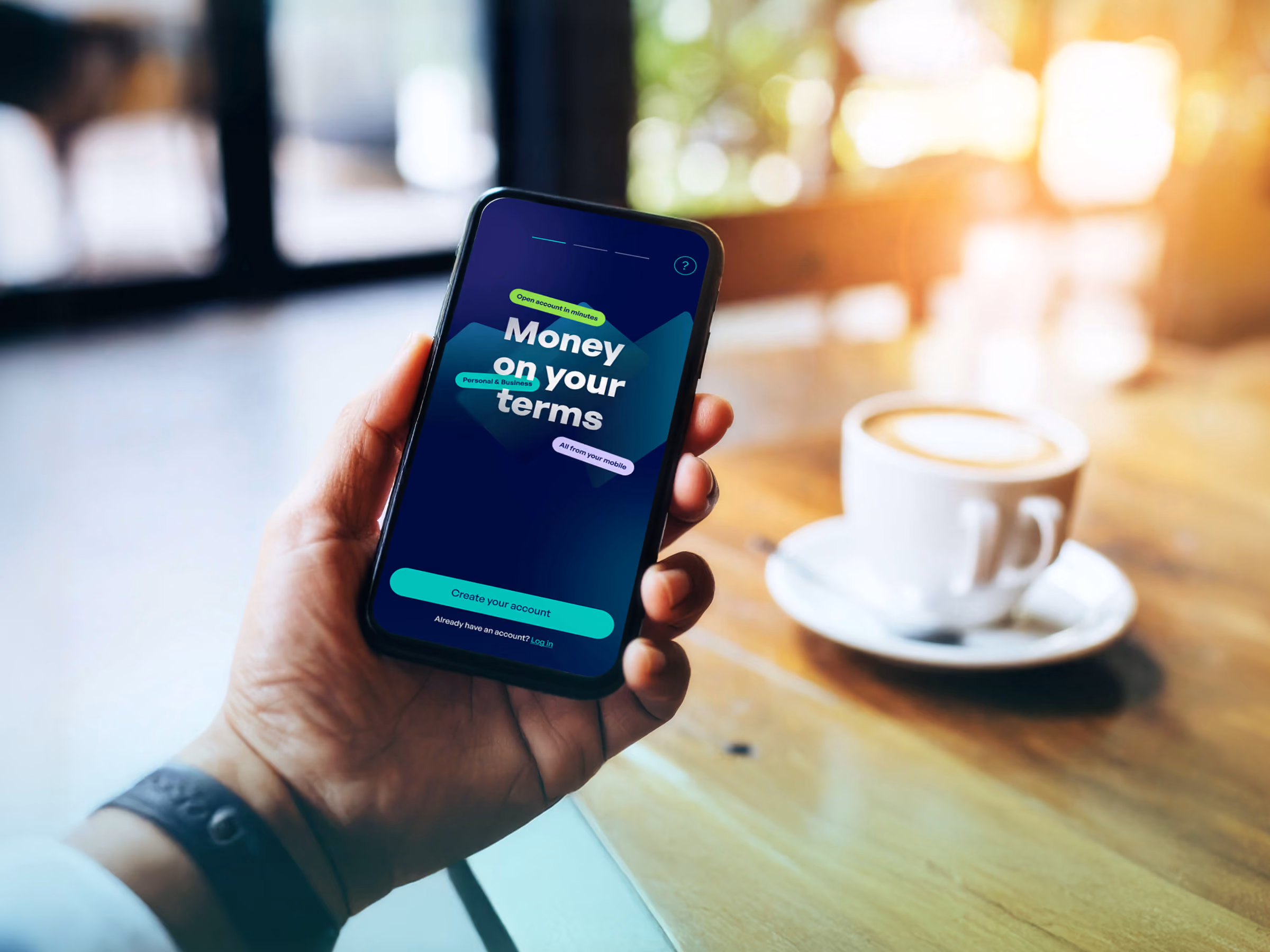 Hand holding a smartphone with a finance app screen and a cup of coffee on a wooden table.