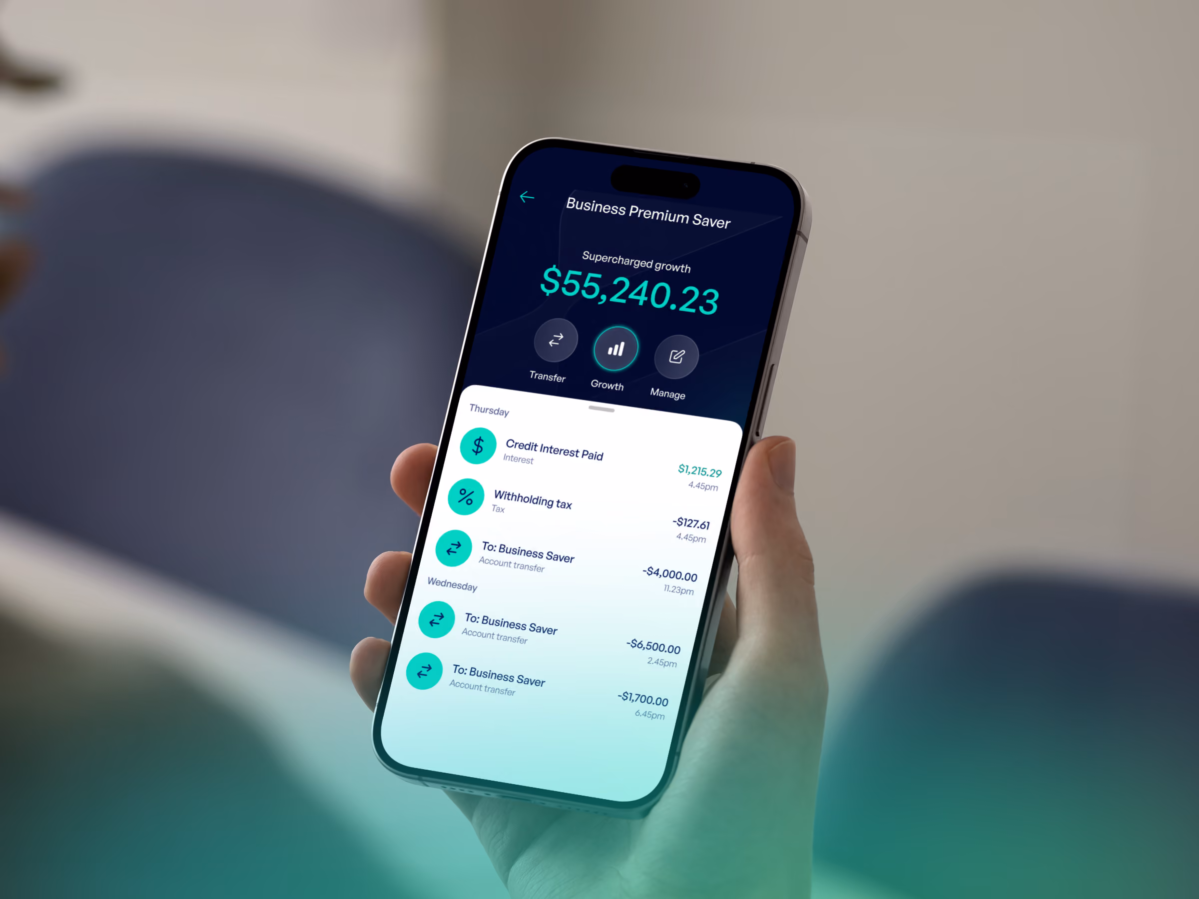 Hand holding phone showing business account balance $55,240.23 and recent transactions.