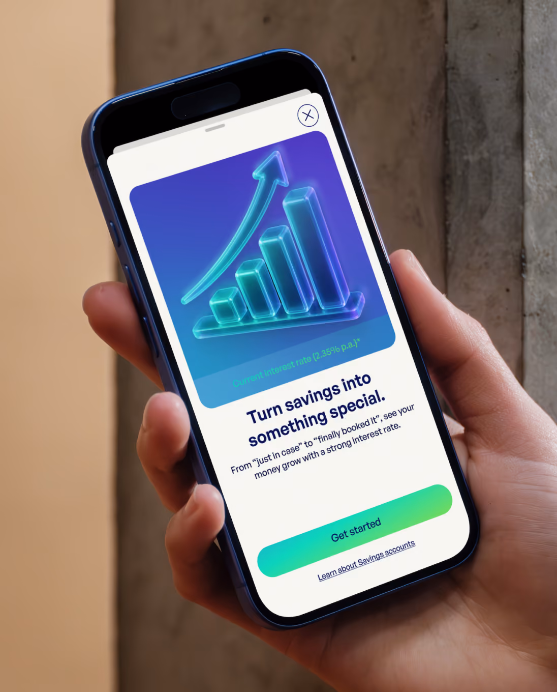 Hand holding phone showing an app screen with an upward trending bar graph and a savings account ad.