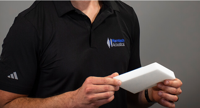 A closeup to the torso of a man while holding a small acoustic pad.